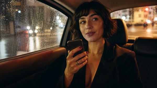 Woman in a taxi pauses before sending a voice message