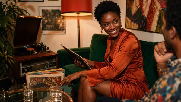 Smiling woman enjoying music and conversation in a colourful living room