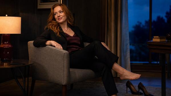 Mature red-haired woman relaxing in a quiet evening sitting room with her phone set aside