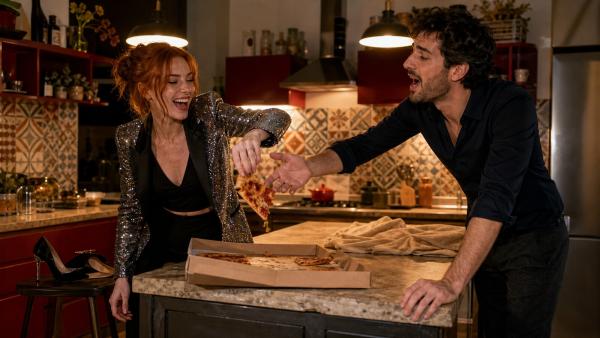 Donna prende una fetta di pizza mentre un uomo prova scherzosamente ad afferrarla